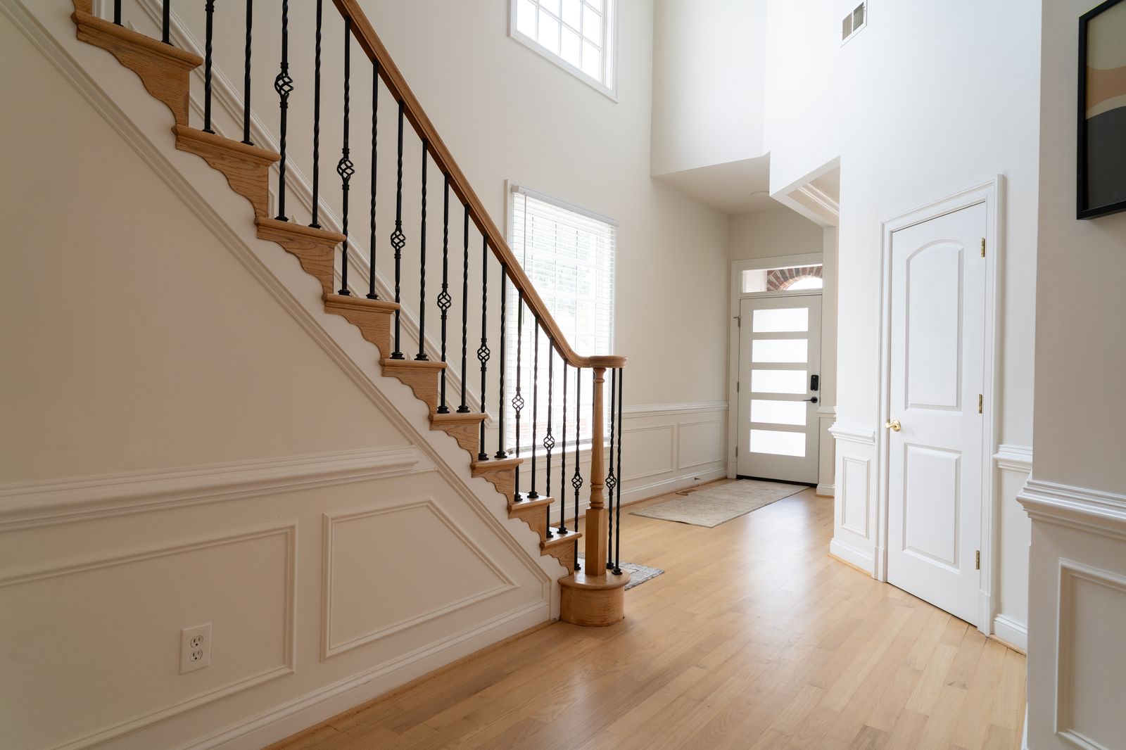Two story foyer with oak staircase and wainscoting